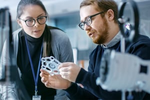 Two professionals examining an additively manufactured metal part