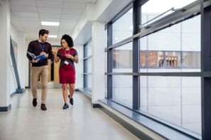 Two executives walking down a hallway, discussing strategy.